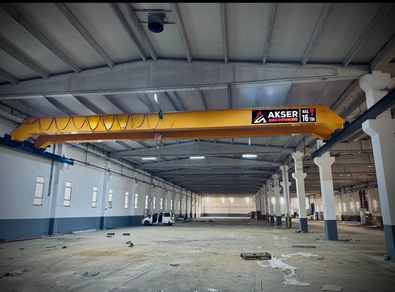 Geniş üretim tesisine kurulmuş sarı AKSER gezer köprülü vinç